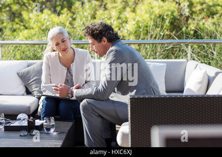 Businessman and businesswoman using digital tablet on balcony patio sofa Stock Photo