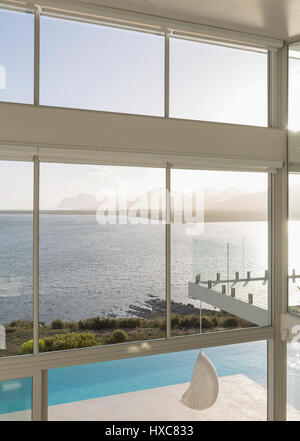 Sunny, tranquil modern luxury home showcase exterior with infinity pool ...