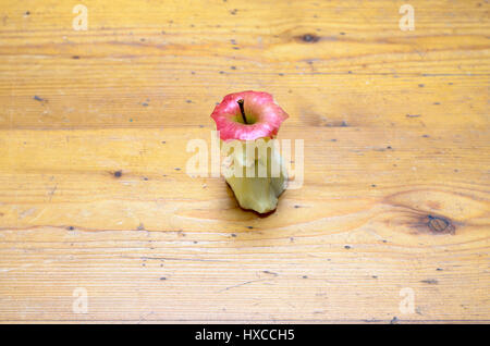 Remaining core of an eaten ripe red apple in a high angle view on a wood table with copy space in a concept of healthy nutrition and diet Stock Photo