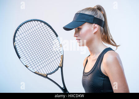 side view of concentrated young woman in tennis unifrorm with tennis racket Stock Photo