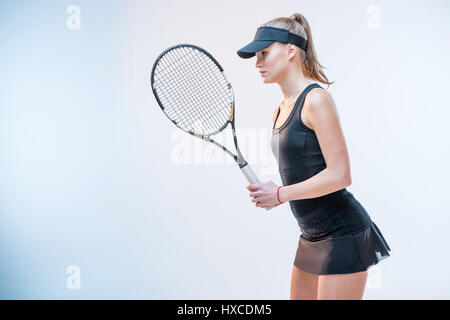 side view of concentrated young woman in tennis uniform with racket in hands Stock Photo