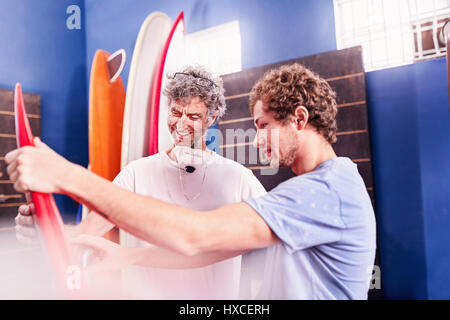 Men making and discussing surfboards in workshop Stock Photo