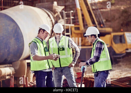 Construction workers meeting, using digital tablet at construction site Stock Photo