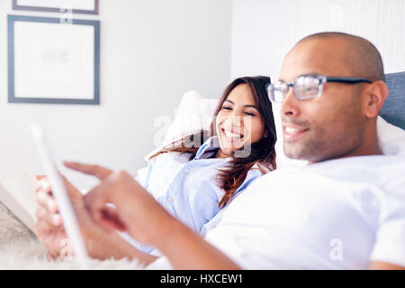 Smiling couple using digital tablet on bed Stock Photo