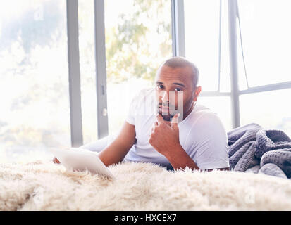 Portrait serious handsome man using digital tablet on bed Stock Photo