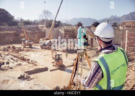 Construction worker surveyor using theodolite at sunny construction site Stock Photo