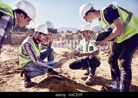 Construction workers and engineers using digital tablets at sunny construction site Stock Photo