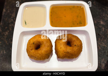 Crispy South Indian breakfast Vada with chutney and sambar on a white partitioned plate Stock Photo