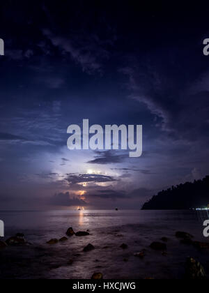 A lightening storm lighting up the night sky in the distance as viewed from the ABC beach on Tioman Island, Malaysia. Stock Photo