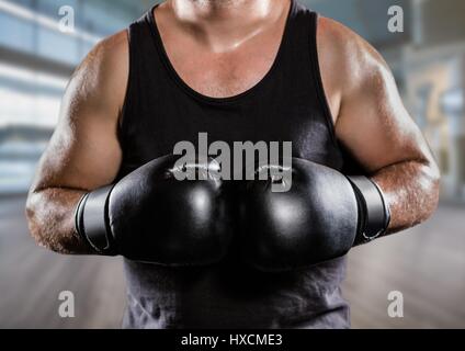 Digital composite of Man with boxing gloves mid sections against blurry gym Stock Photo