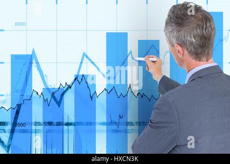 Digital composite of Business man writing on wall with financial graphs Stock Photo