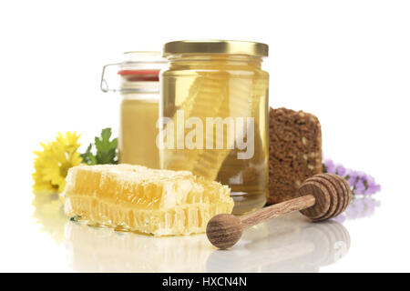 Honey glasses with honeycomb, wholemeal bread, honey spoon and flowers, Honeycomb jars with honey, wholemeal bread, honey and flowers spoon |, Honiggl Stock Photo