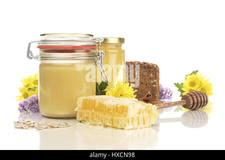 Honey glasses with honeycomb, wholemeal bread, honey spoon, sunflower cores and flowers, Honeycomb jars with honey, wholemeal bread, honey spoon, sunf Stock Photo