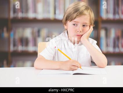 Digital composite of Sad bored boy at desk against bookshelves Stock Photo