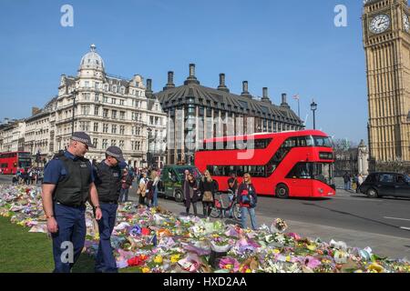 London, UK. 27th March 2017. Police Officers look at floral tributes laid in Parliament Square following the terror attack in Westminster. Credit: claire doherty/Alamy Live News Stock Photo