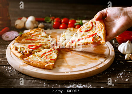 slice of pizza in woman hand over the table with pizza Stock Photo