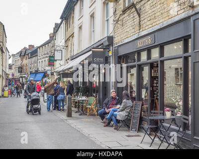 A view up Black Jack Street St in Cirencester with a couple sitting having a coffee drink at Keith's in the foreground