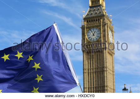 The EU flag, held aloft by an EU supporter, flies in front of Big Ben four days before Article 50 is triggered by the British PM. Stock Photo