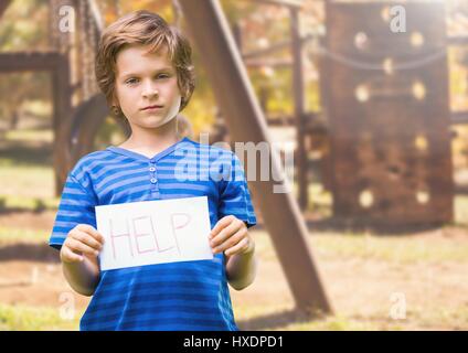 Digital composite of Sad boy holding help sign against playground Stock Photo