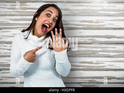 Digital composite of Engaged Woman with ring excited against wood Stock Photo