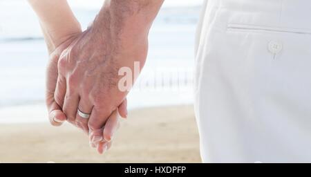 Digital composite of Wedding coupe holding hands by sea Stock Photo