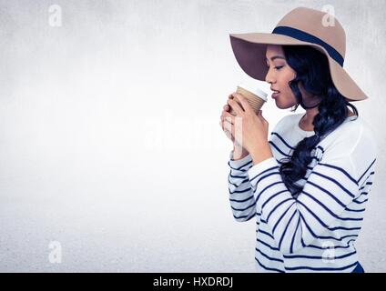 Digital composite of Woman with hat drinking from coffee cup against white wall Stock Photo