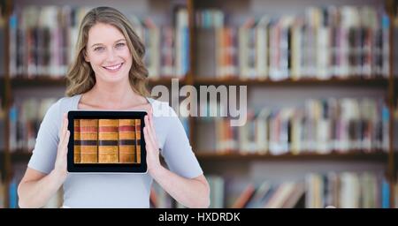 Digital composite of Woman with tablet showing book spines against blurry bookshelf Stock Photo