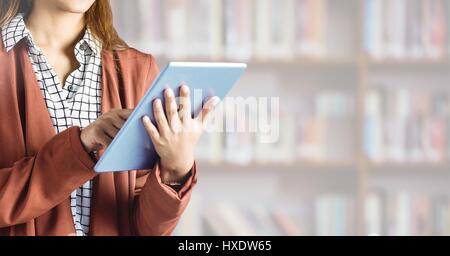 Digital composite of Womans hands on tablet in Library Stock Photo