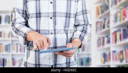 Digital composite of Womans hands on tablet in Library Stock Photo