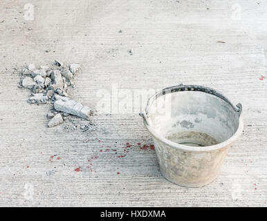 Dirty plastic bucket on the cement floor of the construction site. Stock Photo
