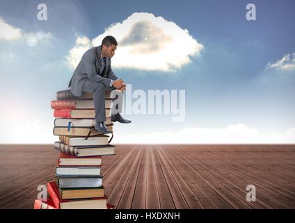 Digital composite of Businessman sitting on Books stacked by blue cloudy sky Stock Photo