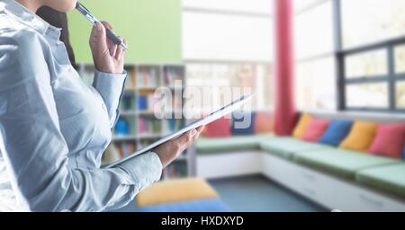 Digital composite of Womans hands holding tablet in Library Stock Photo
