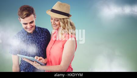 Digital composite of Couple with tablet against blue green background with clouds Stock Photo