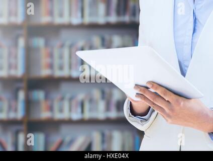 Digital composite of Womans hands holding tablet in Library Stock Photo