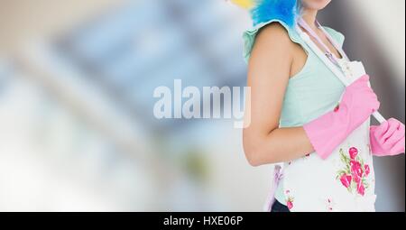 Digital composite of Woman in apron with duster against blurry window Stock Photo