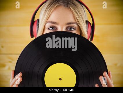 Digital composite of Woman with headphones and record against yellow wood panel Stock Photo