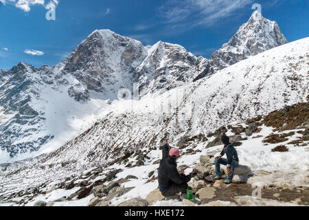 Khumbu Region, Nepal - 13 March 2015: Two sherpas looking at high mountains in the Himalayas region Stock Photo