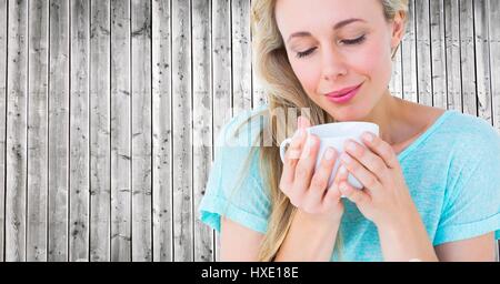 Digital composite of Close up of woman looking down at white cup against grey wood panel Stock Photo