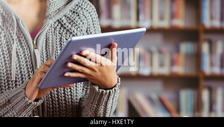 Digital composite of Woman on tablet in Library Stock Photo