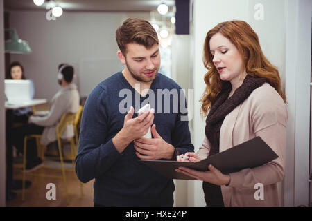 Male and female executives discussing over a file in office Stock Photo