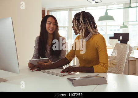 Two female executives working on computer at desk in office Stock Photo