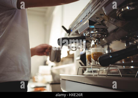 Midsection of male barista making coffee using coffee machine in cafe Stock Photo