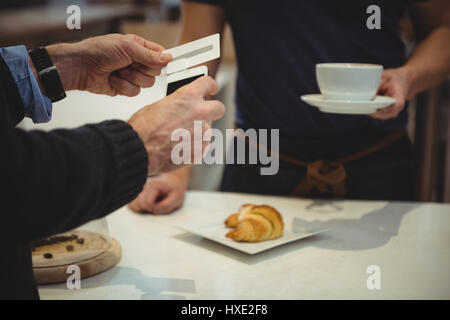 Male customer making payment with smartphone in coffee shop Stock Photo