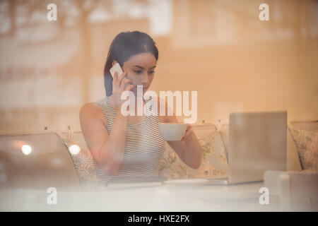 Businesswoman talking on phone while having coffee in cafe Stock Photo