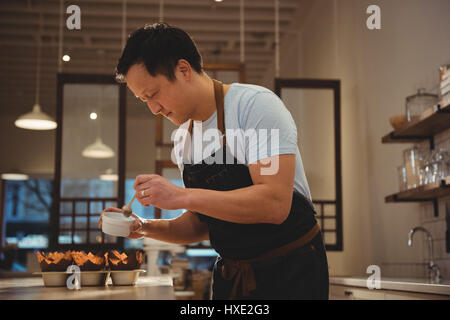 Side view of male barista preparing dessert in coffee shop Stock Photo