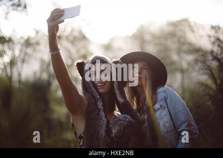 Female friends talking selfie on mobile phone in forest Stock Photo