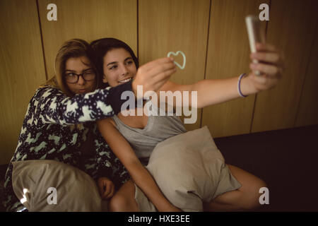 Friends taking selfie on mobile phone in bedroom Stock Photo