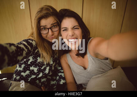 Portrait of friends making faces in bedroom Stock Photo