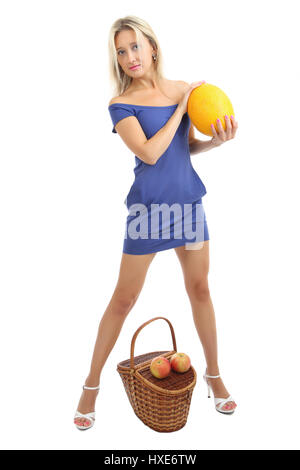 Young caucasian woman 34 years old, with blond hair in a short skin-tight blue dress, is a full-length, near the wicker basket holding a melon, vertic Stock Photo