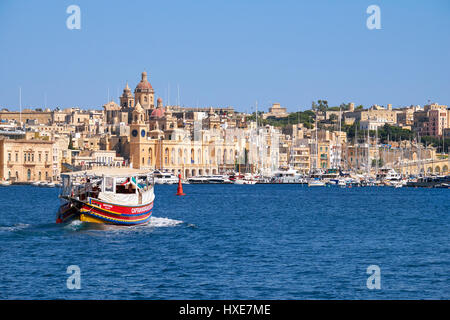 Birgu, MALTA - JULY 24, 2015:  The view of historical buildings of Birgu across the Dockyard creek  with the Captain Morgan Cruises ship going to the  Stock Photo